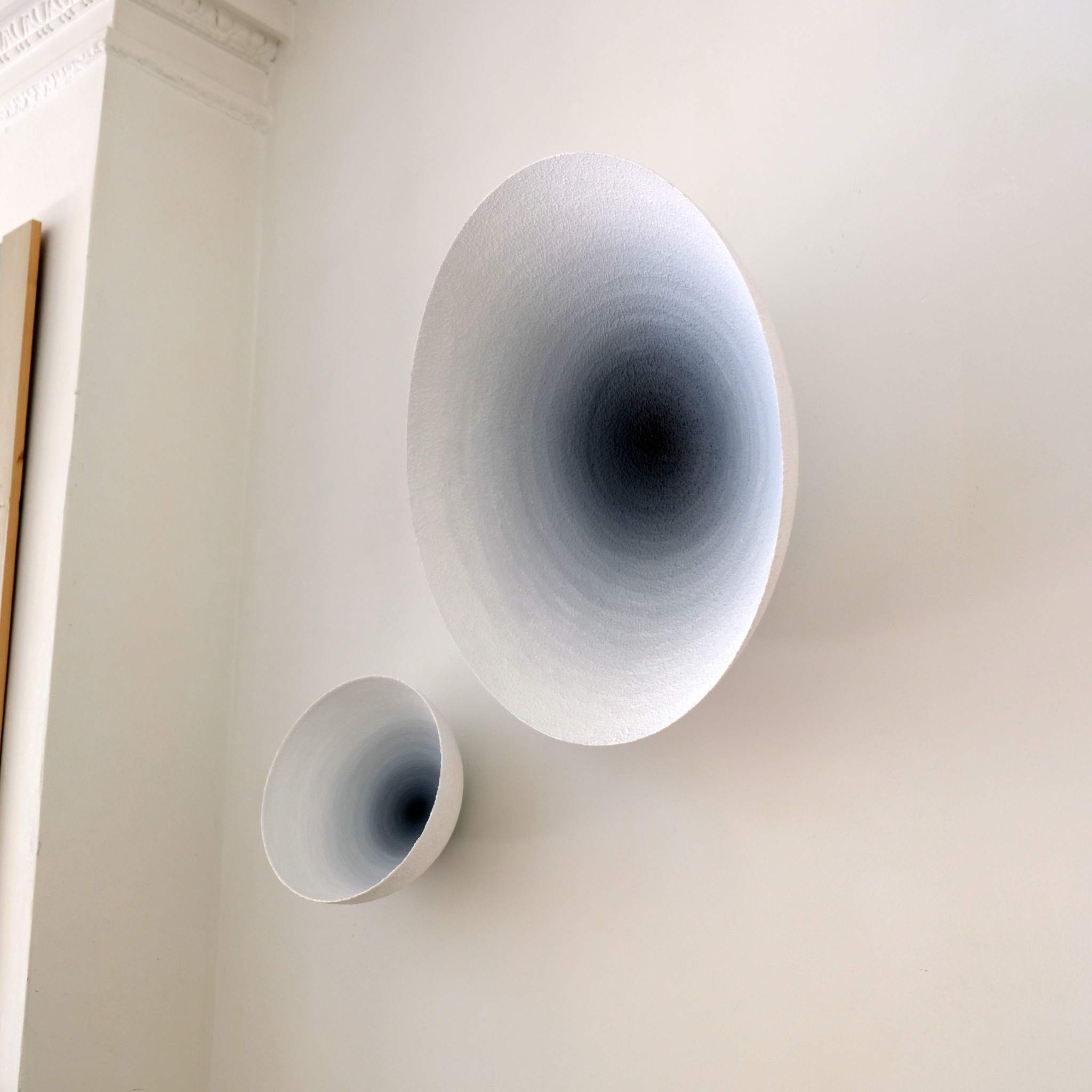 Two white gradient reliefs hanging on a wall